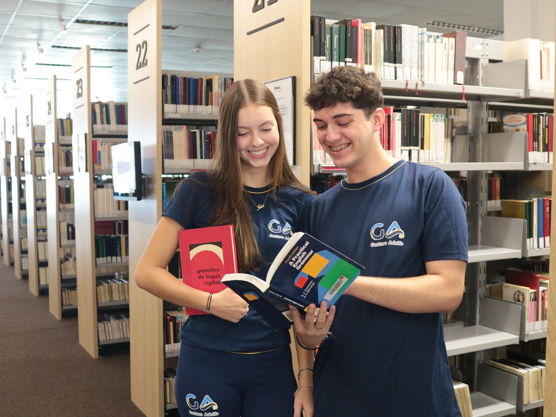 Estudantes do GA escolhendo livros nas estantes da biblioteca